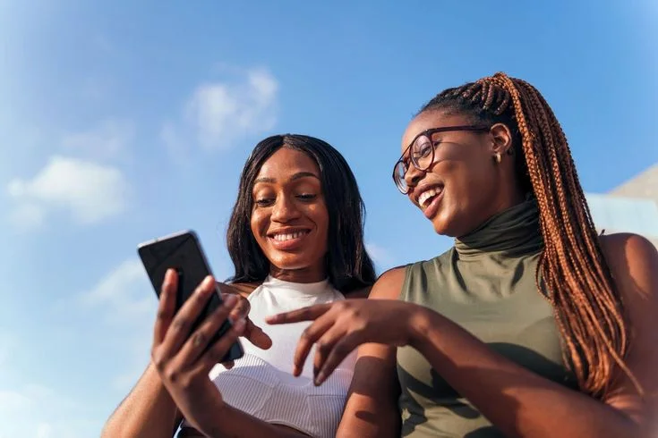 Deux jeunes femmes consultant les réseaux sociaux sur un smartphone